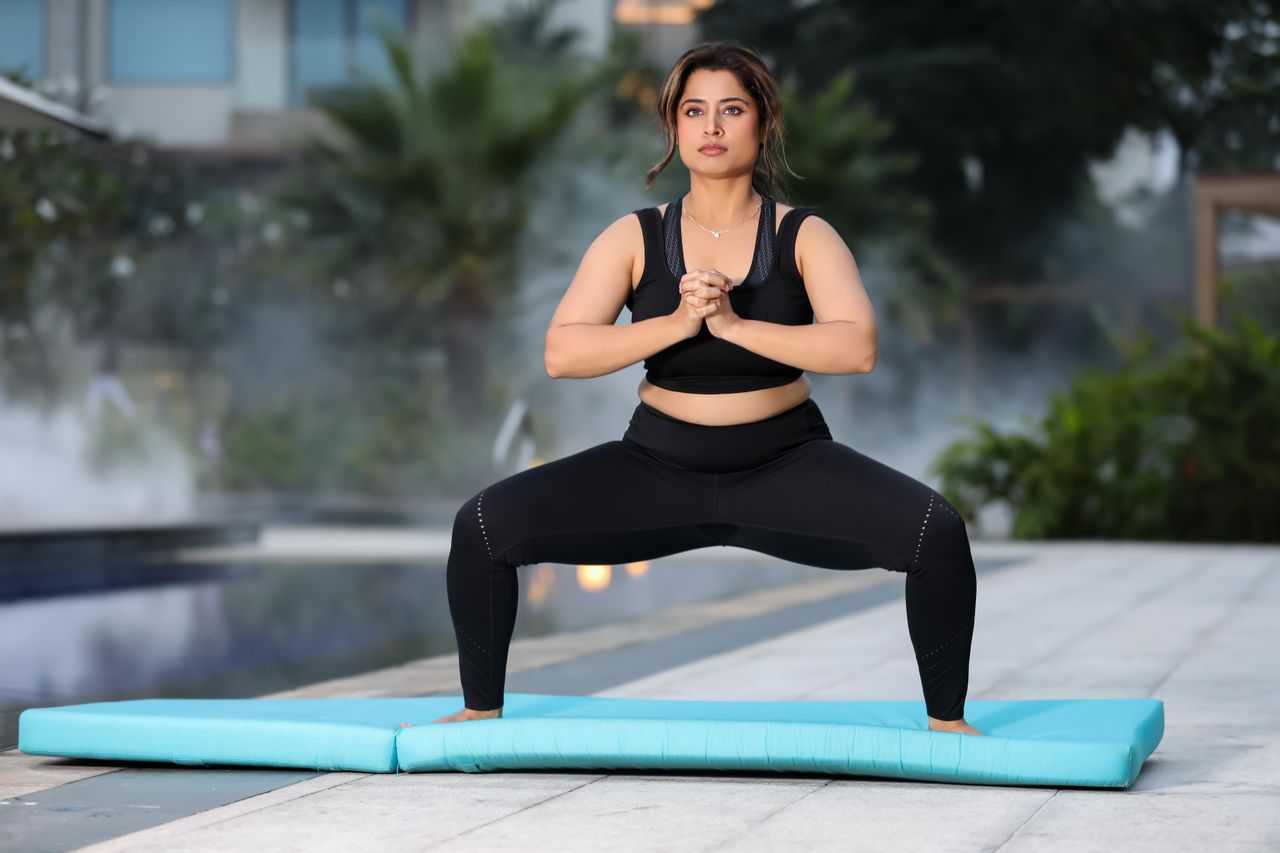 Woman practicing yoga outdoors by the pool, emphasizing fitness and relaxation in a serene environment.
